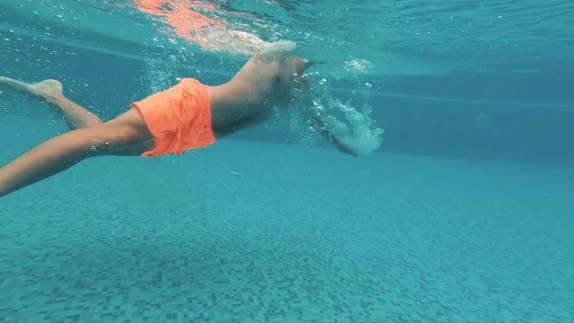 Young guy swims underwater in a swimming pool