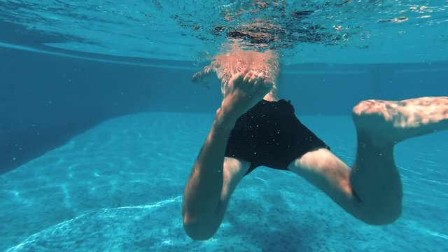 Young guy swims underwater in a swimming pool