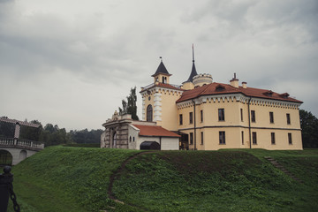 Fototapeta na wymiar Yellow castle with brown roof in cloudy weather