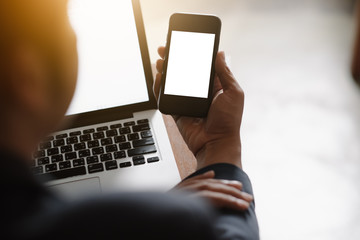 Mockup image of a man's hand holding white mobile phone with blank black desktop screen on thigh in cafe
