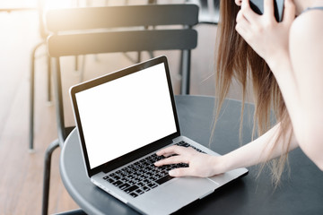 Mockup image of a businesswoman using laptop with blank white desktop screen with coffee cup on wooden table in cafe