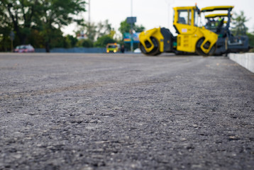 Close up view on the new asphalt road on which steamroller is working. Construction site.