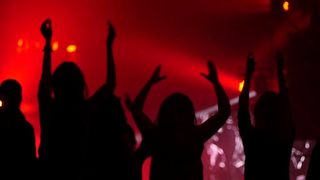 Girl fan silhouettes raise hands dancing enjoying music concert in lumiere