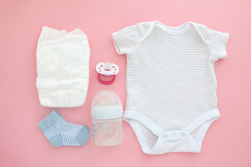 Set for a newborn nipple bottle diaper socks baby body slippink background top view
