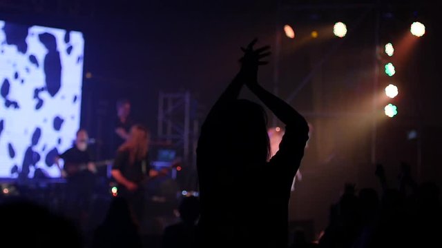 Girl fan silhouette raise clapping hands enjoying music concert in flashing lumiere