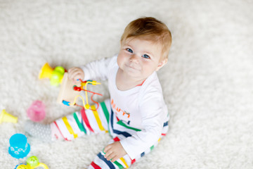Adorable baby girl playing with educational toys in nursery. Happy healthy child having fun with...