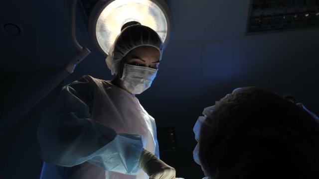A female surgeon performs an operation for a patient