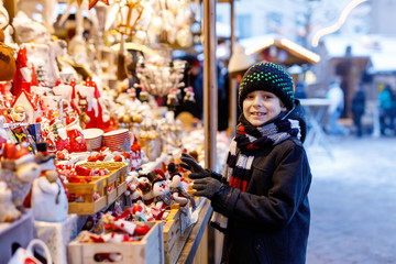 Little cute kid boy selecting decoration on Christmas market. Beautiful child shopping for toys and decorative ornaments