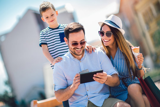 Smiling parents and little boy with tablet pc and credit card outdoor