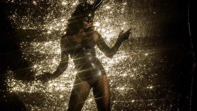 woman dances with large bunny ears mask and black latex body against sparkling background. great clip for disco, party and events
