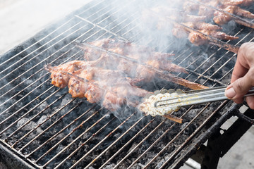 Chicken wings on barbecue grill with fire smoking.