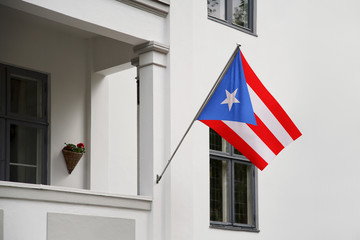 Puerto Rico flag. Puerto Rican flag hanging on a pole in front of the house. National flag of waving on a home displaying on a pole on a front door of a building. Flag raised at a full staff.