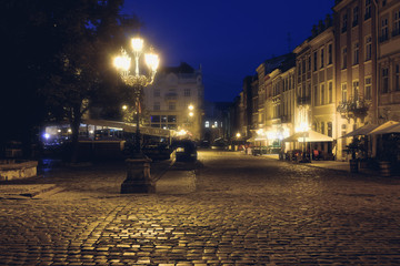 Old European city pedestrian street night city lights. Old architeccture illuminated street
