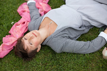 Beautiful young woman resting on green grass