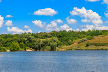 Fototapeta na wymiar Summer landscape with beautiful lake, green meadows, hills, trees and blue sky