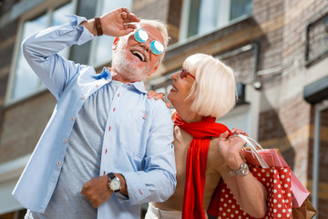 After shopping. Waist up of adorable elderly stylish couple enjoying a walk together while holding...