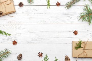 Gifts for new year wrapped in craft paper near spruce branches and cones on white wooden background...