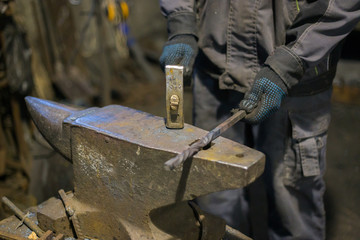 Professional blacksmith forging molten metal on anvil at smithy, workshop. Handmade, craftsmanship and blacksmithing concept