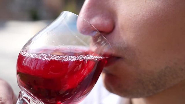 Closeup man mouth drinking juice from wine glass outdoors