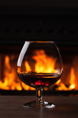 a glass of cognac in front of fireplace