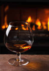 a glass of cognac in front of fireplace