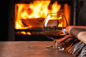 a glass of cognac in front of fireplace - obrazy, fototapety, plakaty