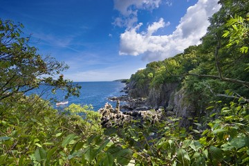 Sheer cliffs of the northern coast of Bornholm island - Helligdomsklipperne (Sanctuary Rocks), Gudhjem town in the background, Denmark