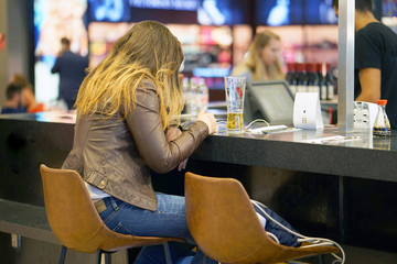 A girl drinks beer in the airport's cafe-bar and waits for her flight. A girl drinks beer in a cafe...