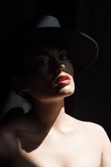 beautiful stylish girl in black felt hat posing in dark