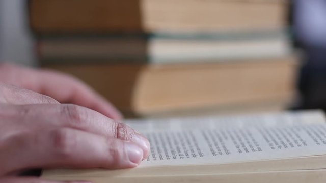 Fingers closeup leafing reading a real paper book in slow motion
