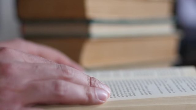 Fingers closeup leafing reading a real paper book in slow motion