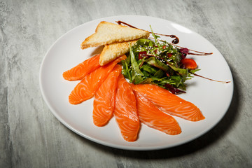 top view on salmon slices served with rucola and tomato salad and toasted bread