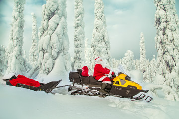 Authentic Santa Claus is riding a snowmobile through the winter forest.