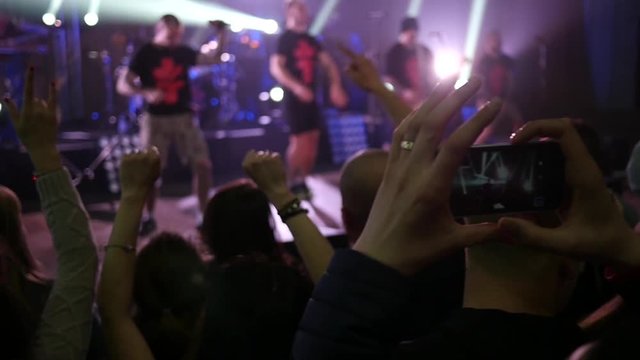 Dancing cheering crowd fan spectators rais hands at concert lumiere spot lights