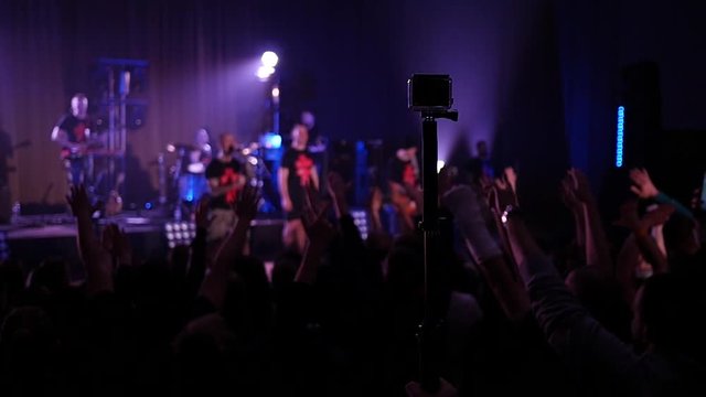 Crowd fan spectators silhouettes raise swaying hands at concert light lumiere