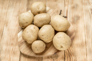 Fototapeta na wymiar Raw potato tubers on a wooden background.
