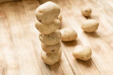 Raw tubers of potatoes in the form of a pyramid on a wooden background.