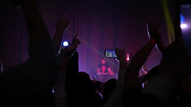 Cheering crowd fan spectators silhouettes rais hands at concert lumiere