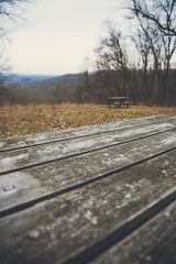 Vintage Wooden Picnic Table in Park with Rolling Hills on a Grey Winter Day.