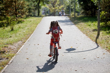 Alone little girl riding a bike in the Park in summer