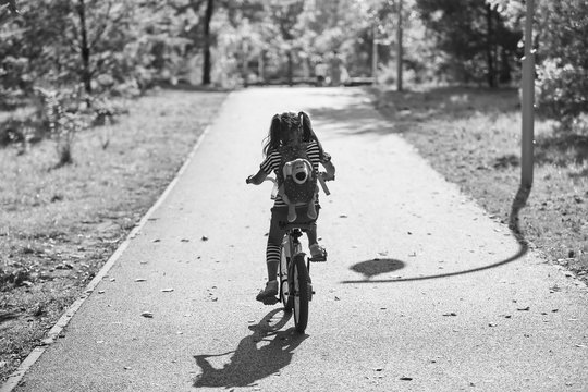 Alone little girl riding a bike in the Park in summer