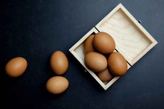Huevos de gallina ecológicos dentro de una caja de madera en un fondo oscuro
