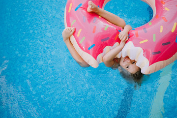 Little girl swimming with inflatable donut in the swimming pool
