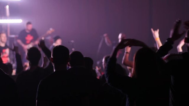 Dancing fan spectators silhouettes at a concert flashing lumiere jump raise hands