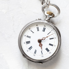 used silver pocket watch on light gray plaster