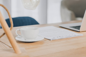 laptop, documents and cup of tea on wooden table in office