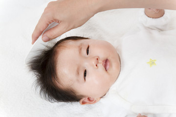 Obraz na płótnie Canvas 新生児の沐浴後の髪を梳かす方法を説明するマニュアル用写真。湯上りに頭髪、髪の毛を櫛で梳かしている様子のクローズアップ