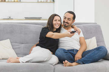 Smiling young couple relaxing and watching TV at home