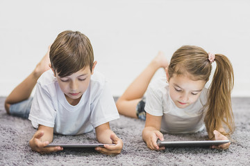 Siblings together on the floor using tablet