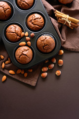 Homemade chocolate muffins (brownies) with cinnamon, almonts and hazelnuts on brown paper background